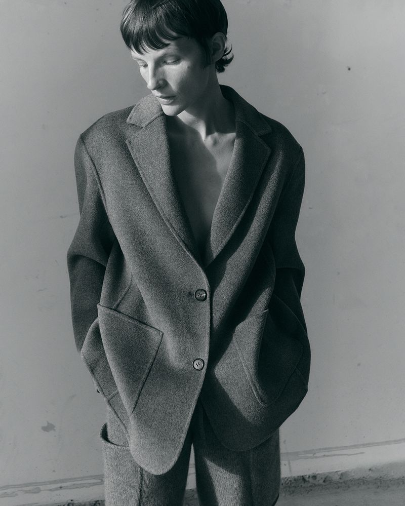 Model Sara Blomqvist looking down while wearing an oversized tailored wool blazer and matching trousers in monochrome.