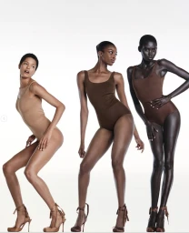 Three models wearing matching brown bodysuits and lace-up high heels against a white background