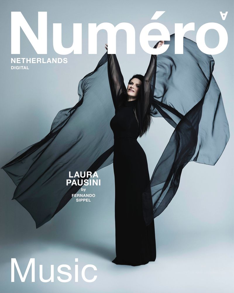 Laura Pausini posing in a flowing black gown with sheer wing-like sleeves on the cover of Numéro Netherlands Digital.