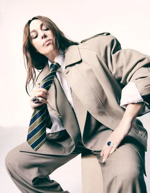 Monica Bellucci wearing a beige suit and striped tie against a plain white background for Madame Figaro editorial.