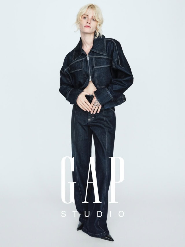 Model Esther Rose McGregor wearing a dark denim zip jacket and matching jeans against a white backdrop for Gap Studio.