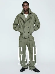 Model Alton Mason posing in an olive green double-breasted jacket and matching cargo trousers against a white seamless background.