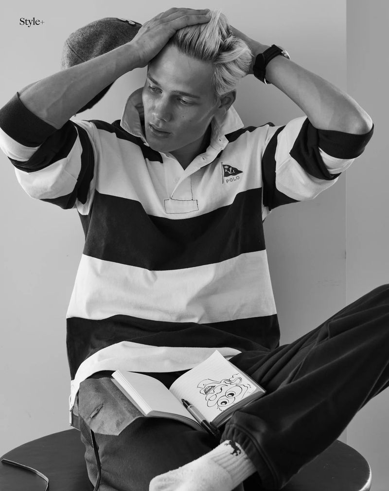 Model Blue River Wild seated wearing a black and white striped rugby shirt with an open sketchbook on his lap.