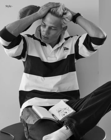 Model Blue River Wild seated wearing a black and white striped rugby shirt with an open sketchbook on his lap.