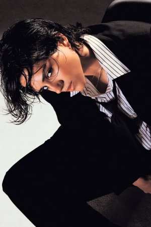 Sasha Calle posing in an oversized black suit and striped collared shirt with wet-look hair for Numéro Netherlands.