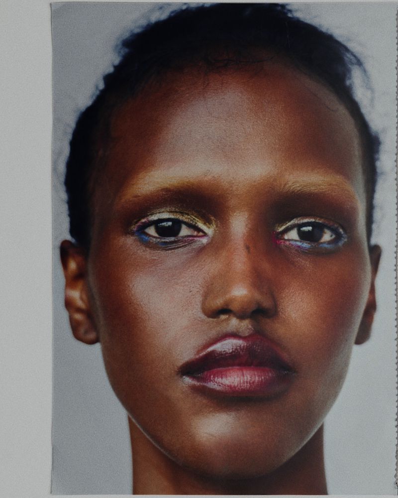 Close-up beauty portrait of model Maryamo Musse with bleached eyebrows, shimmering eyeshadow, and berry-toned lips.