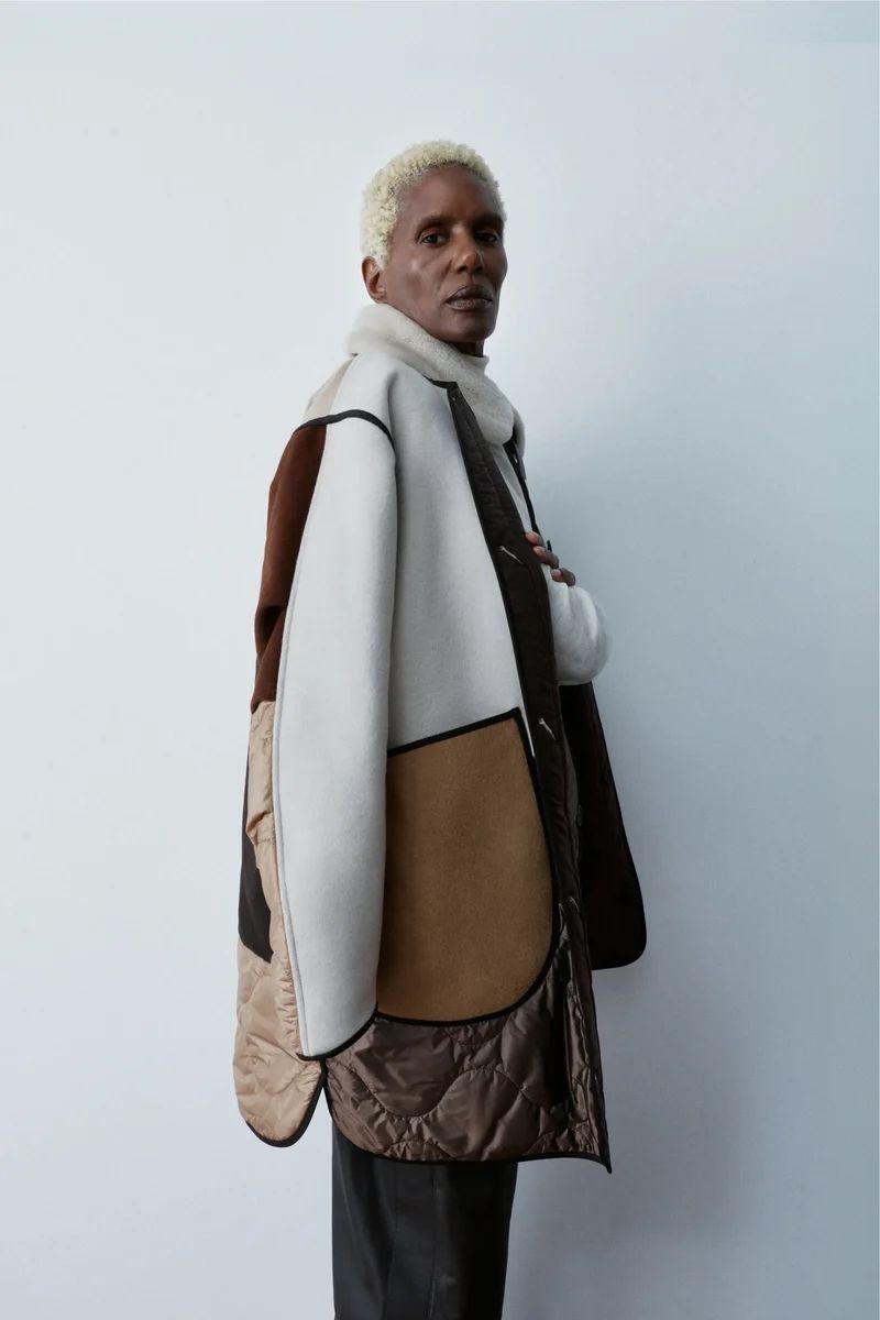 Model Amanda Parker poses in a multi-toned shearling and quilted coat against a clean white backdrop.