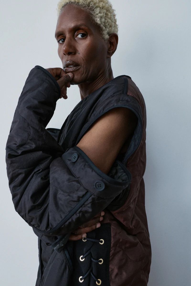 Model Amanda Parker in a black quilted modular jacket with lace-up detail against a plain studio backdrop.