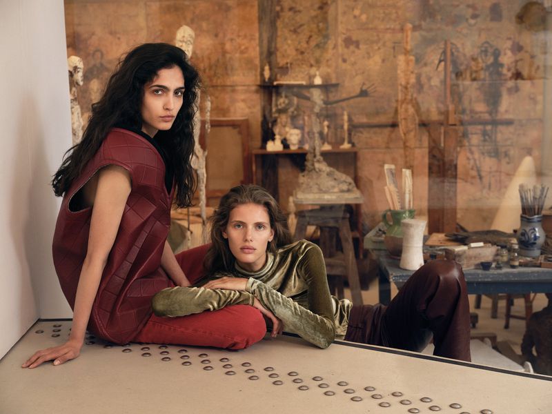 Models Sara Caballero and Rosalieke Fuchs posing in velvet and quilted leather garments in an artist studio setting.
