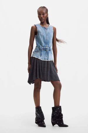 Black female model wearing a sleeveless denim belted top, charcoal skirt, and black grommet boots against a white studio background.