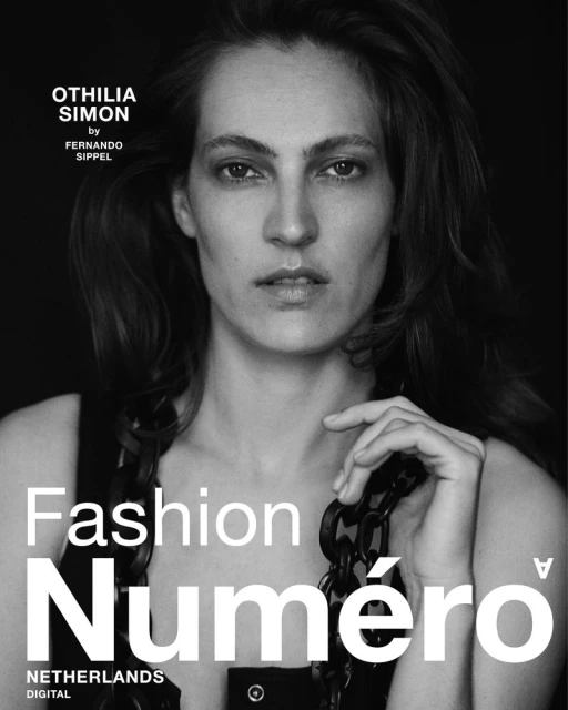 Black and white magazine cover portrait of a woman with dark hair and a chain necklace against a dark backdrop.