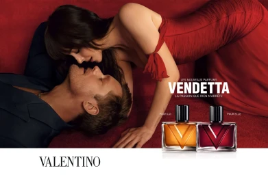 Dakota Johnson in a red dress and Alexander Skarsgard in a dark suit lying together in a Valentino Vendetta perfume campaign.