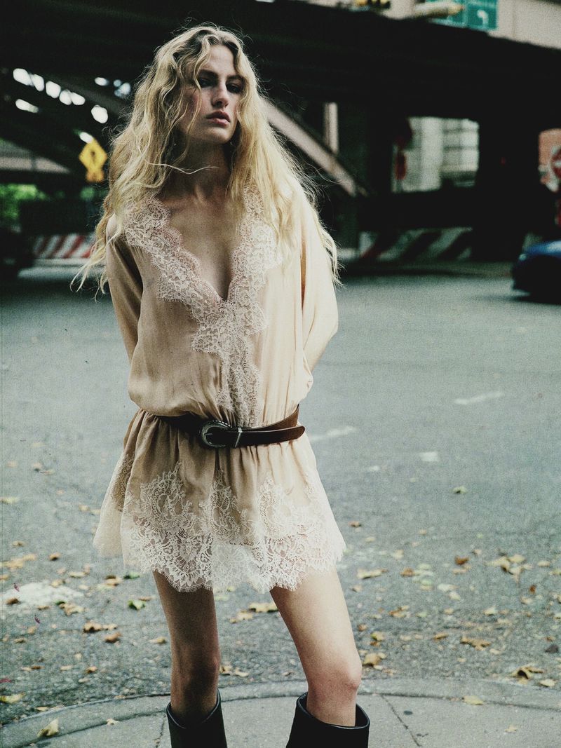 Model Felice Nova Noordhoff in a beige lace-trimmed mini dress with a leather belt on a city street.