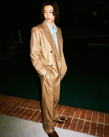 Yuta Jinguji standing poolside at night in an oversized brown tailored double-breasted suit and blue shirt.