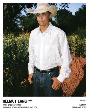 Man in a straw cowboy hat, white button-up shirt, and dark blue jeans outdoors for Helmut Lang Jeans.