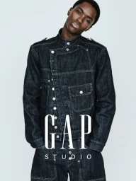 Alton Mason wears a dark raw denim jacket with asymmetric silver buttons against a neutral backdrop for GapStudio.