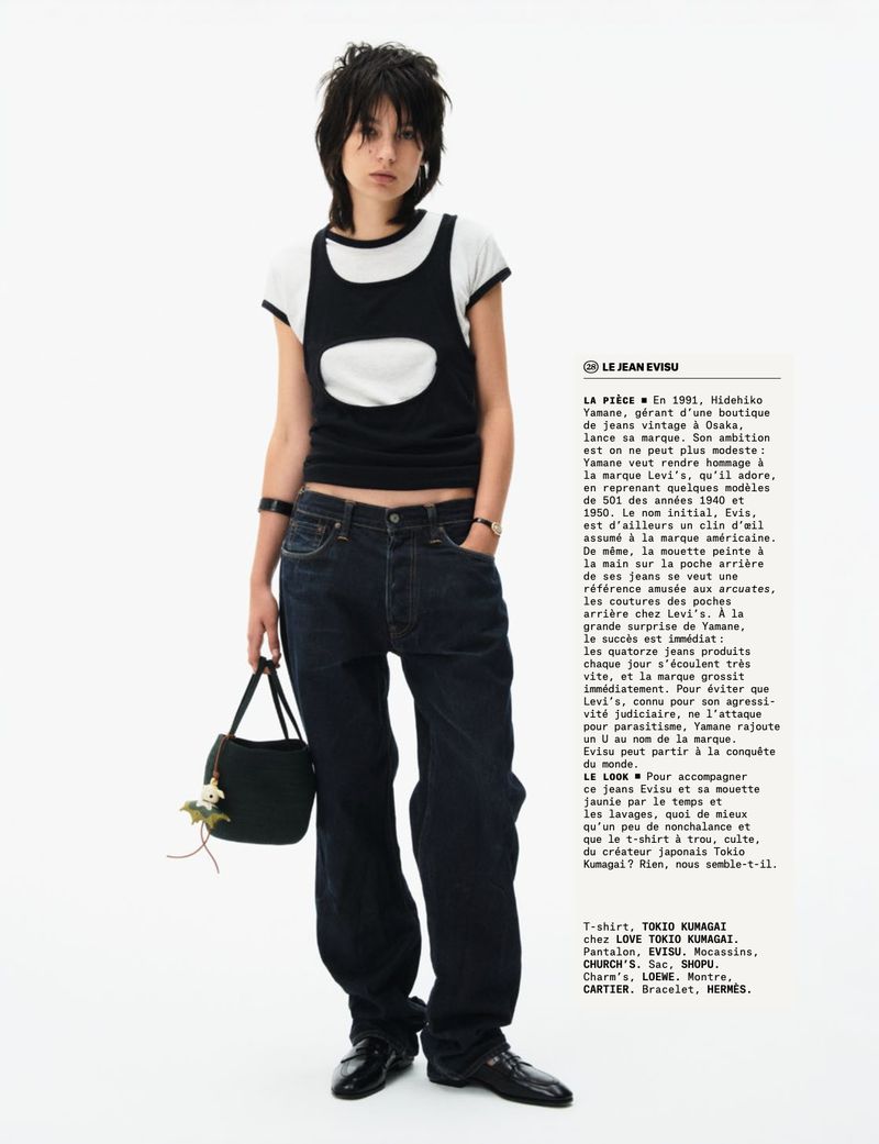 An adult female poses in wide-leg jeans and a black and white top against a bright white background, carrying a small black purse.