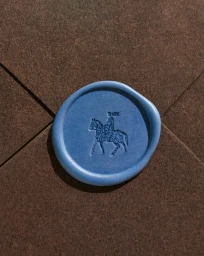 Blue wax seal featuring an embossed knight on horseback affixed to a brown textured paper envelope.