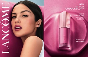 Olivia Rodrigo posing next to a Lancome Lip Idole Cuddleblur lipstick tube in front of a pink textured backdrop.