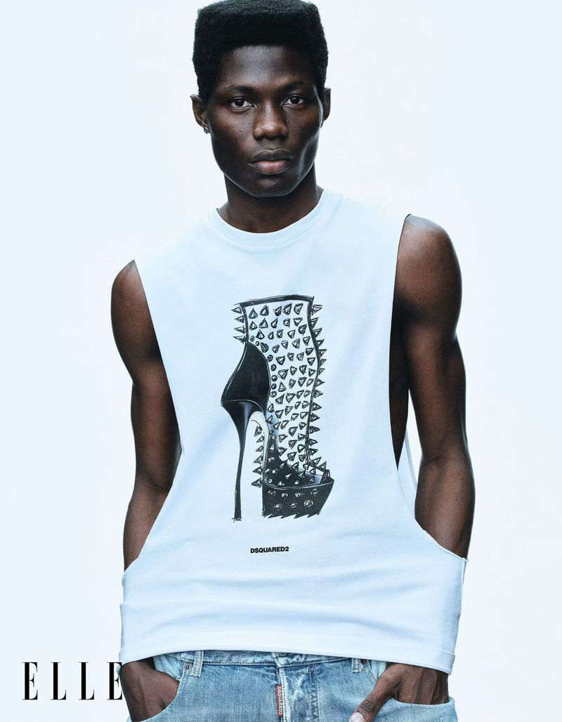 Model Bakare Lekan posing in a white graphic sleeveless shirt and light denim jeans against a bright white background.