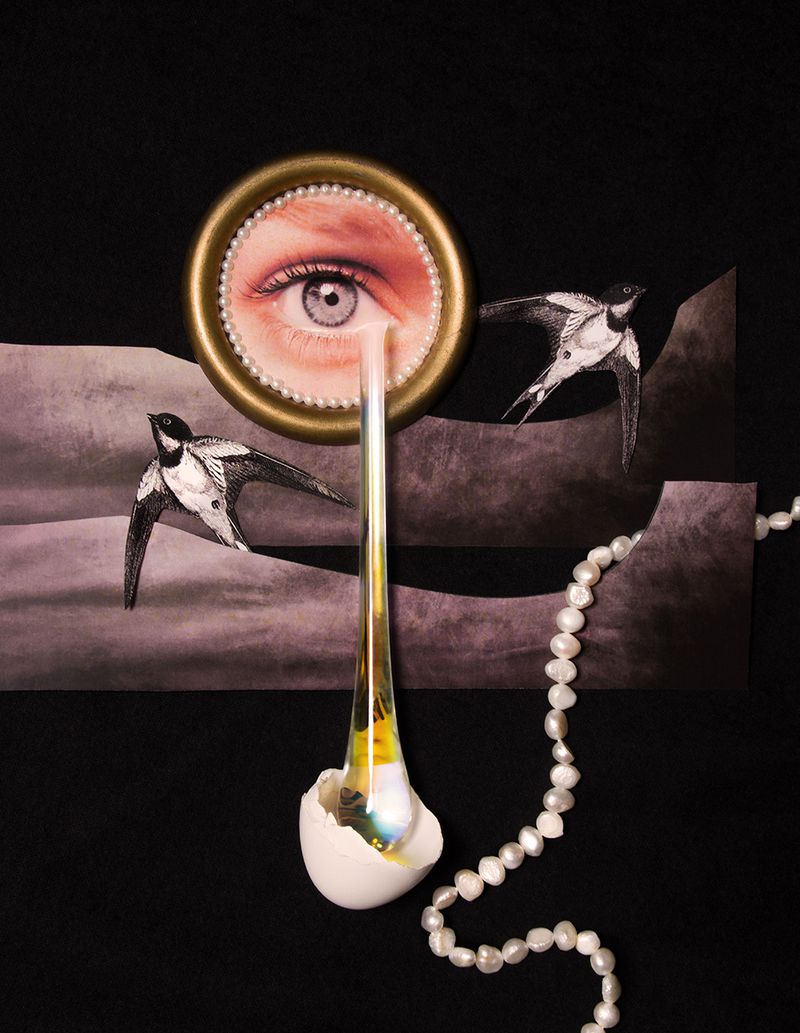Surreal collage featuring a framed eye shedding a glass teardrop into an eggshell with illustrated swallows and pearls on black.