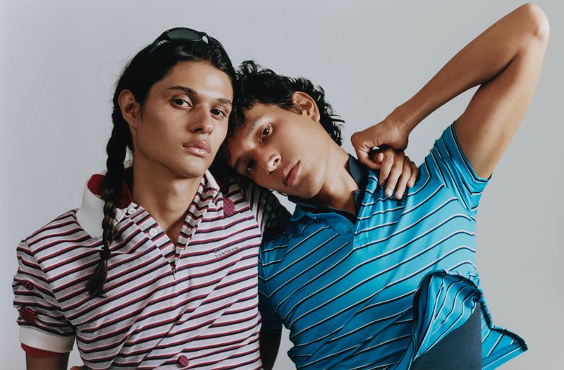 Two men posing closely in striped polo shirts against a neutral studio backdrop for M Revista de Milenio.