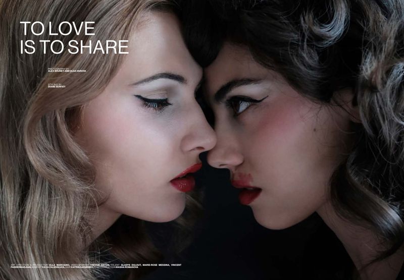 Close-up profile of two women with winged eyeliner and red lips facing each other against a dark background.