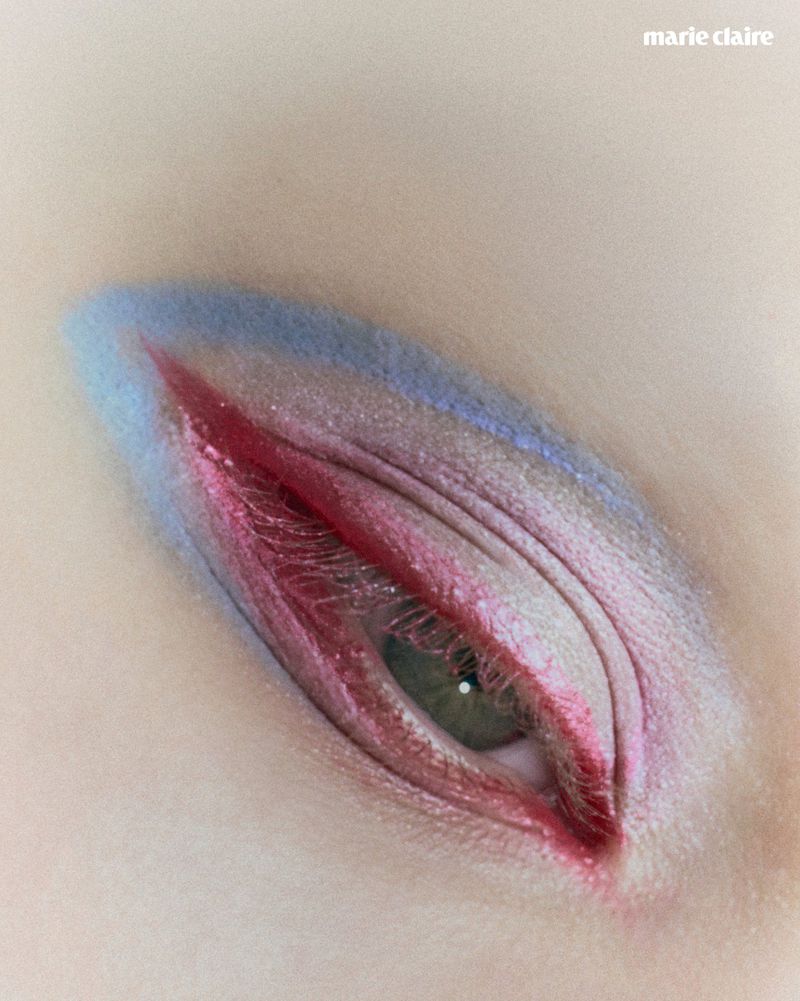 Extreme close-up of a green eye styled with sharp red eyeliner and soft pastel blue eyeshadow for Marie Claire Colombia.
