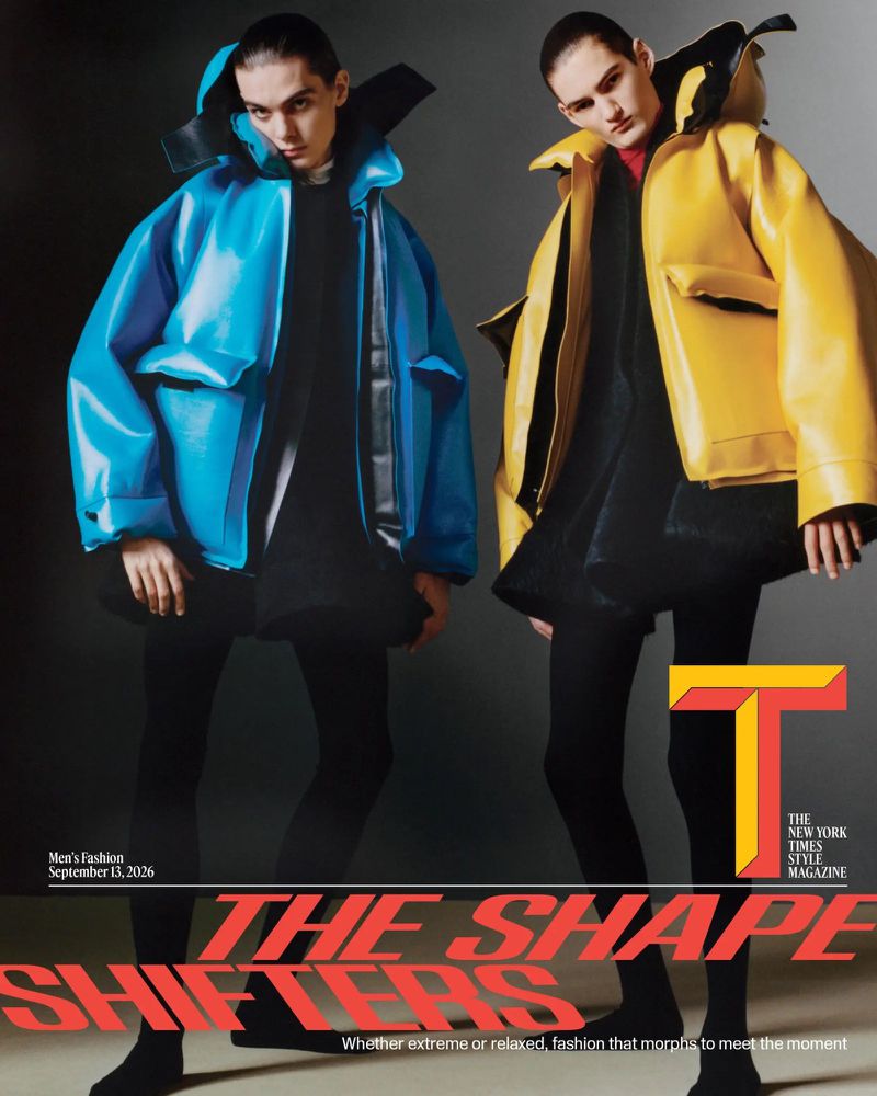 Two male models posing in oversized glossy blue and yellow jackets with black leggings against a dark studio backdrop.