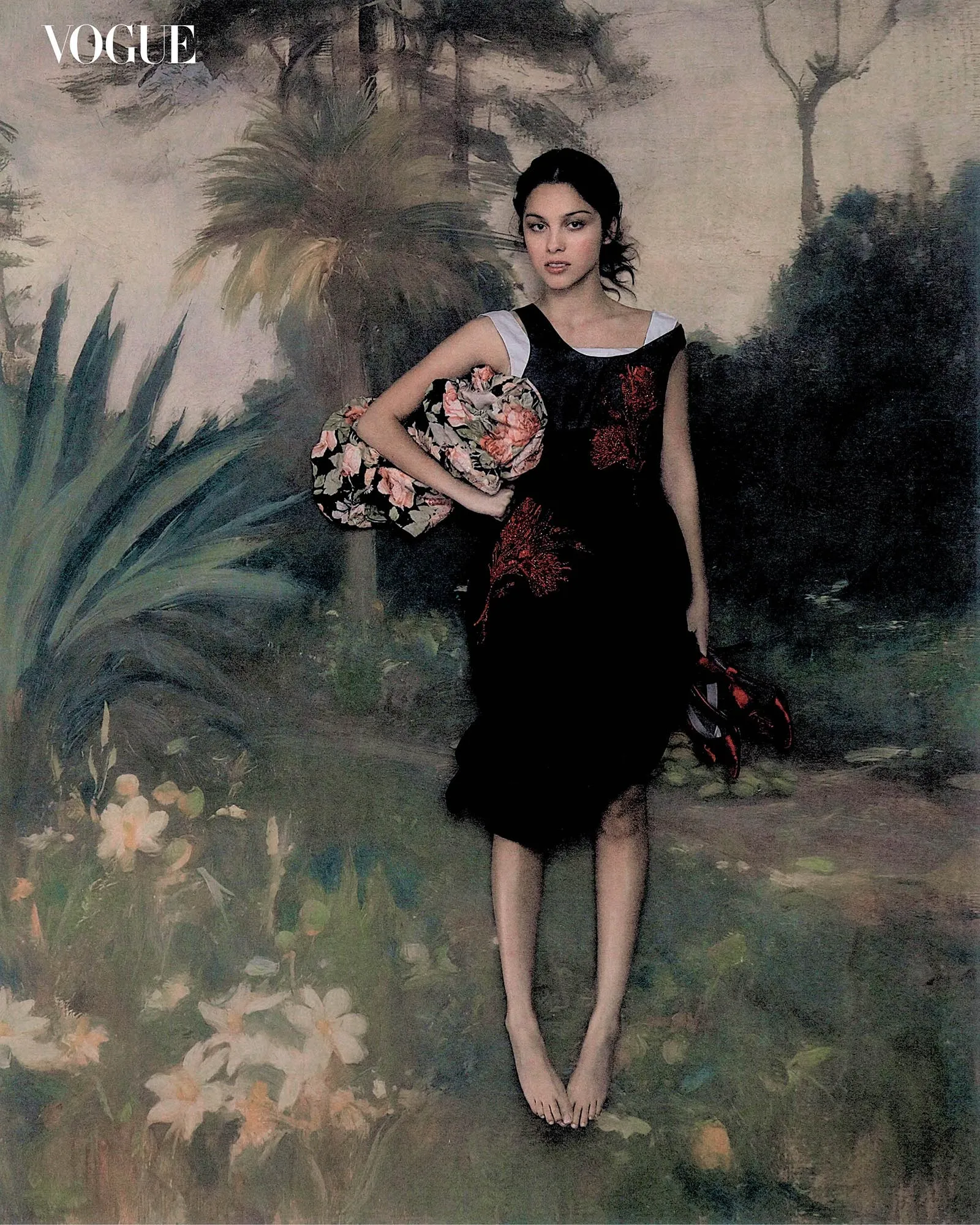 Olivia Rodrigo posing barefoot in a black embroidered dress holding patterned fabric against a painted scenic landscape backdrop.