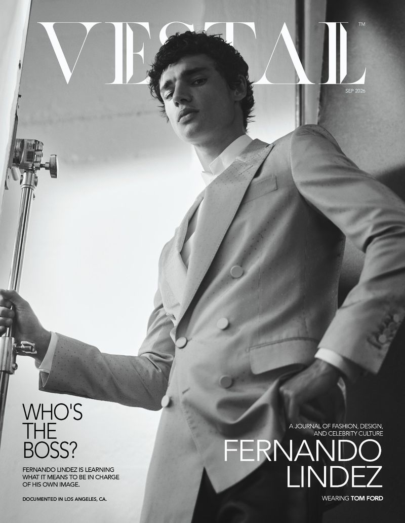 Fernando Lindez posing in a double-breasted suit holding a studio light stand on the black and white cover of Vestal Magazine.