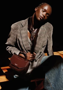 Model wearing a grey blazer and holding a brown leather handbag, photographed by Alasdair McLellan for Emporio Armani.