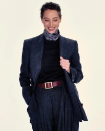 Christy Turlington wearing a dark wool blazer and matching trousers against a neutral background