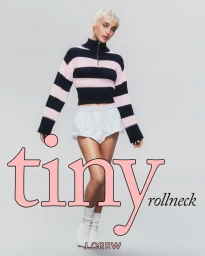Emma Chamberlain wearing a striped zip-neck sweater and white shorts against a seamless grey backdrop for J.Crew.