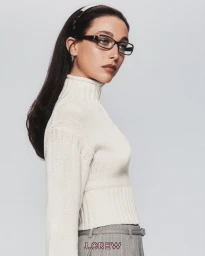 Emma Chamberlain wearing cream turtleneck and eyeglasses for J. Crew Tiny Rollneck campaign against white background.