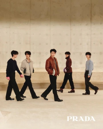 Five male models walking in Prada menswear against a smooth architectural concrete wall.