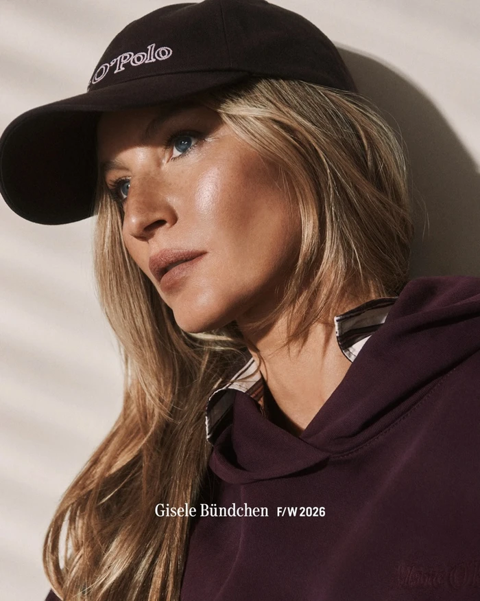 Gisele Bundchen wearing a dark cap and burgundy hoodie in a campaign portrait for Marc OPolo Fall-Winter 2026