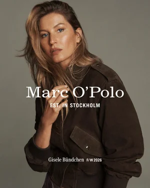 Gisele Bundchen wearing a dark brown suede jacket in an editorial campaign portrait against a grey backdrop