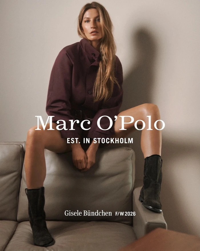 Gisele Bundchen seated on a leather sofa wearing a plum jacket and black boots for Marc O'Polo
