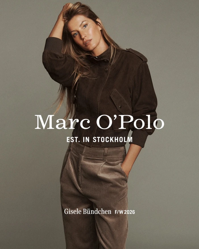 Gisele Bundchen wearing a dark brown jacket and corduroy trousers against a neutral grey seamless background for Marc O'Polo.