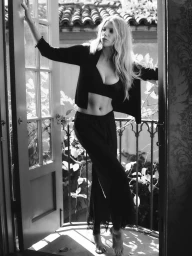 Charlotte McKinney in black crop top and trousers standing in a doorway for NakedCashmere Boudoir project