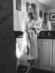 Charlotte McKinney in a white robe standing in a domestic bathroom for NakedCashmere Boudoir campaign