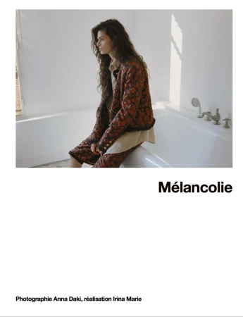 Model Avishag Amir wearing a patterned tweed jacket seated on the edge of a white bathtub in an editorial for Numéro France.