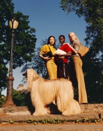 Three models standing outdoors with an Afghan Hound dog next to a lamppost for Tory Burch Fall-Winter 2026 campaign.