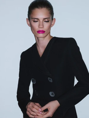 Model Wilda Rubin wearing a black double-breasted blazer with bright fuchsia lipstick against a seamless studio backdrop.