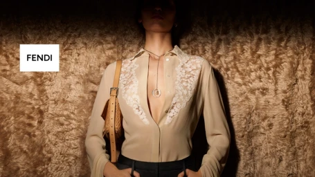 Model in cream lace-trimmed shirt wearing a tan leather handbag against a textured brown fur background for Fendi
