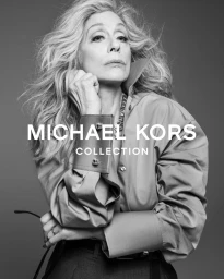 Black and white portrait of actress Judith Light wearing an oversized collared shirt with wide cuffs for Michael Kors Collection.