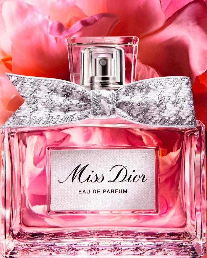 Miss Dior perfume bottle with silver bow against vibrant pink peony petals background