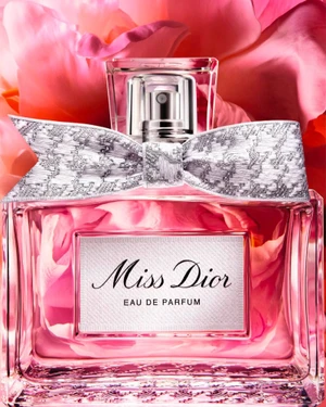 Miss Dior perfume bottle with silver bow against vibrant pink peony petals background