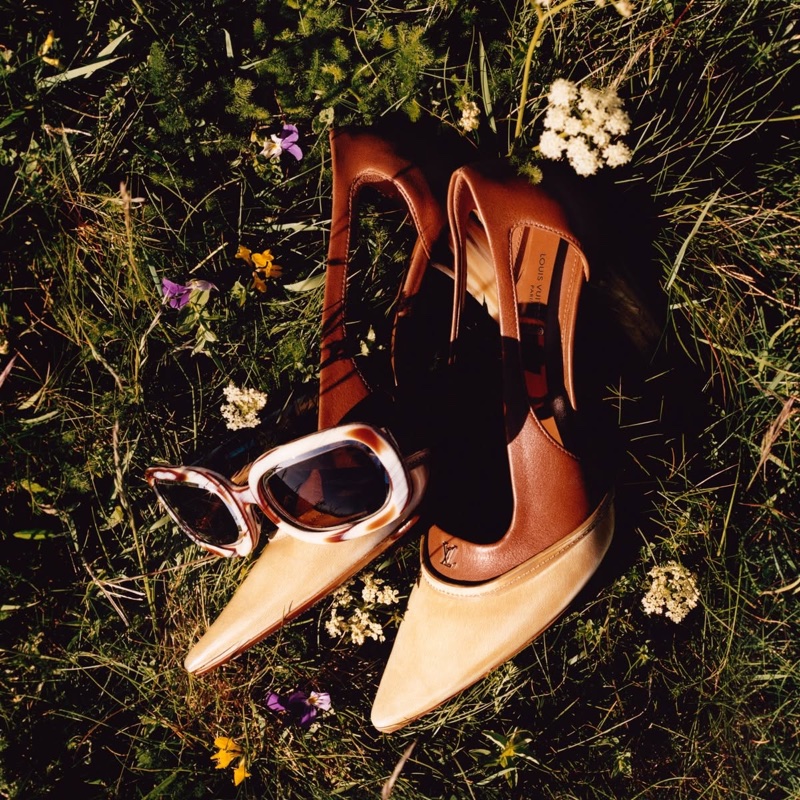 Brown leather high heels and tortoiseshell sunglasses resting on lush green grass